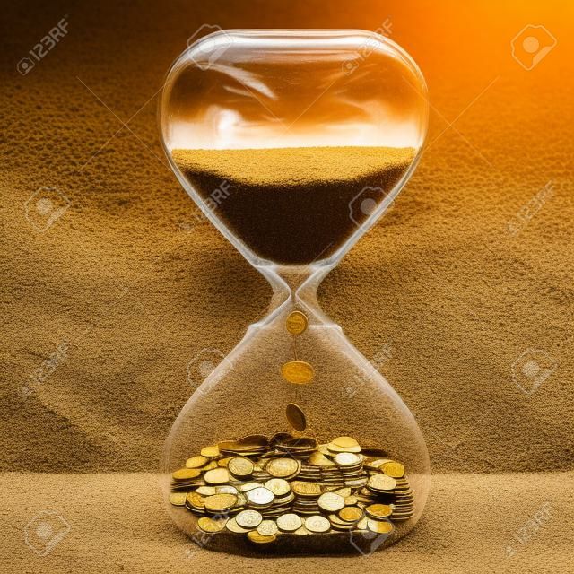 时间是金钱金融机会概念沙时钟与灰尘和硬币孤立在灰色墙壁背景