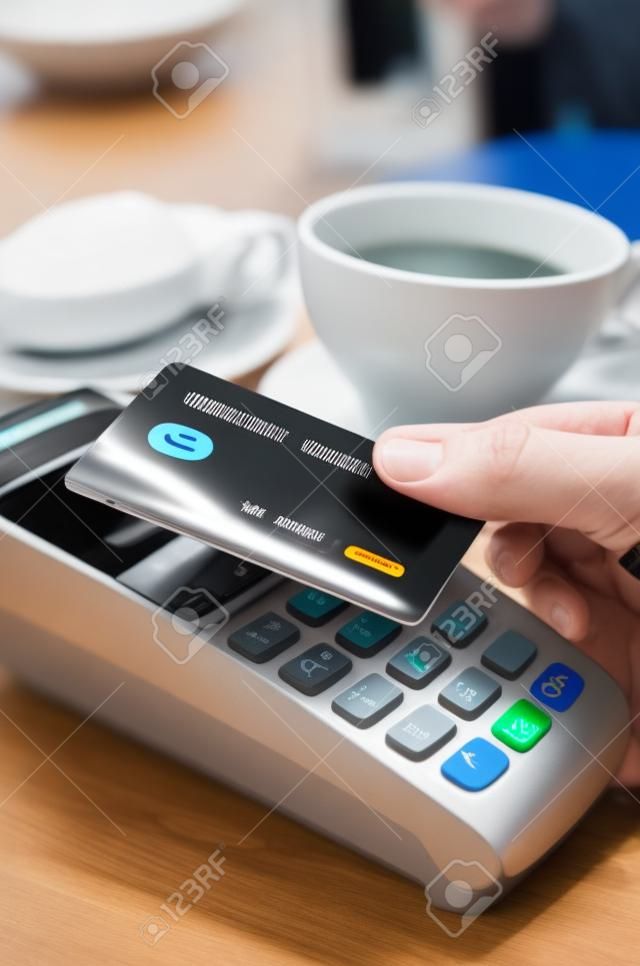 L'uomo con terminale di pagamento con tecnologia contactless NFC nella caffetteria