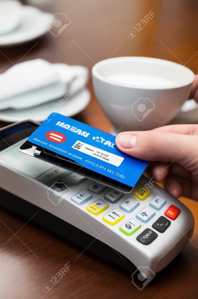 L'uomo con terminale di pagamento con tecnologia contactless NFC nella caffetteria