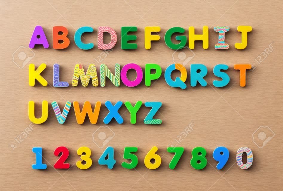 Kolorowe magnesy na papierze alfabetu na tablicy. Litery ustawione samodzielnie na białym tle