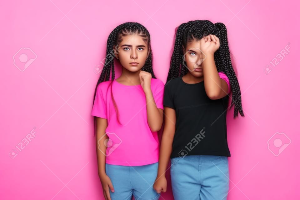 분홍색 배경 위에 고립된 채 평상복을 입고 머리띠를 땋은 화난 10대 소녀 2명의 이미지