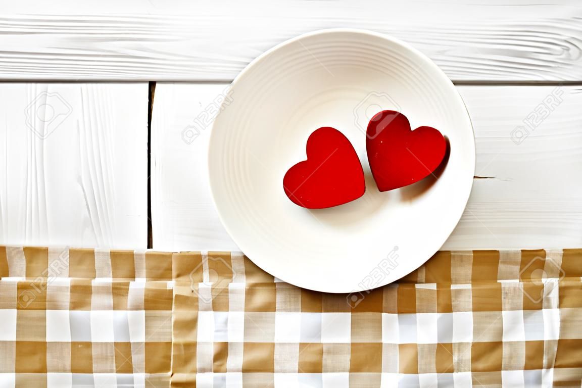 Two red hearts in a white bowl on rustic wood