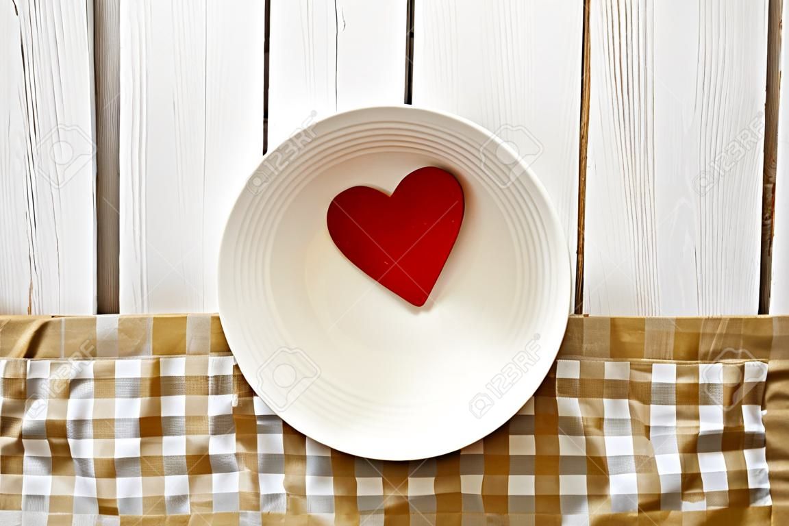 Two red hearts in a white bowl on rustic wood