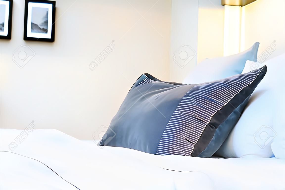 Bello cuscino comodo di lusso sul letto con la decorazione leggera della lampada nell'interno della camera da letto