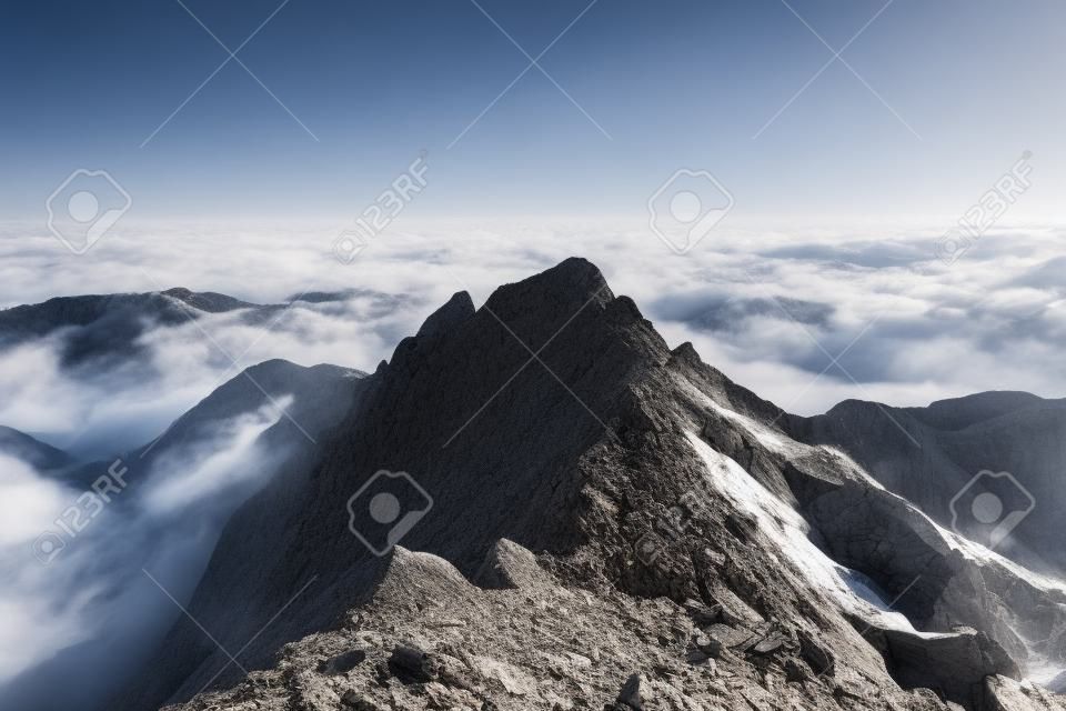 Jagged rocky ridge and high mountain peak summit in a misty atmospheric alpine landscape