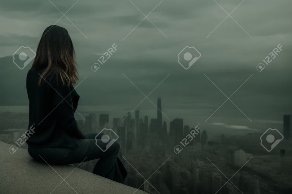 Woman wearing black sweater and facing away from camera while sitting in foreground above large metropolis