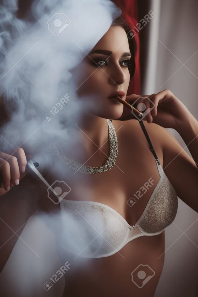Мода фото великолепной женщины с длинными волосами в нижнем белье, курение ciragette, создает в интерьере
