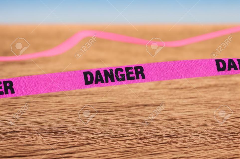 Pink danger boundary tape in a field.