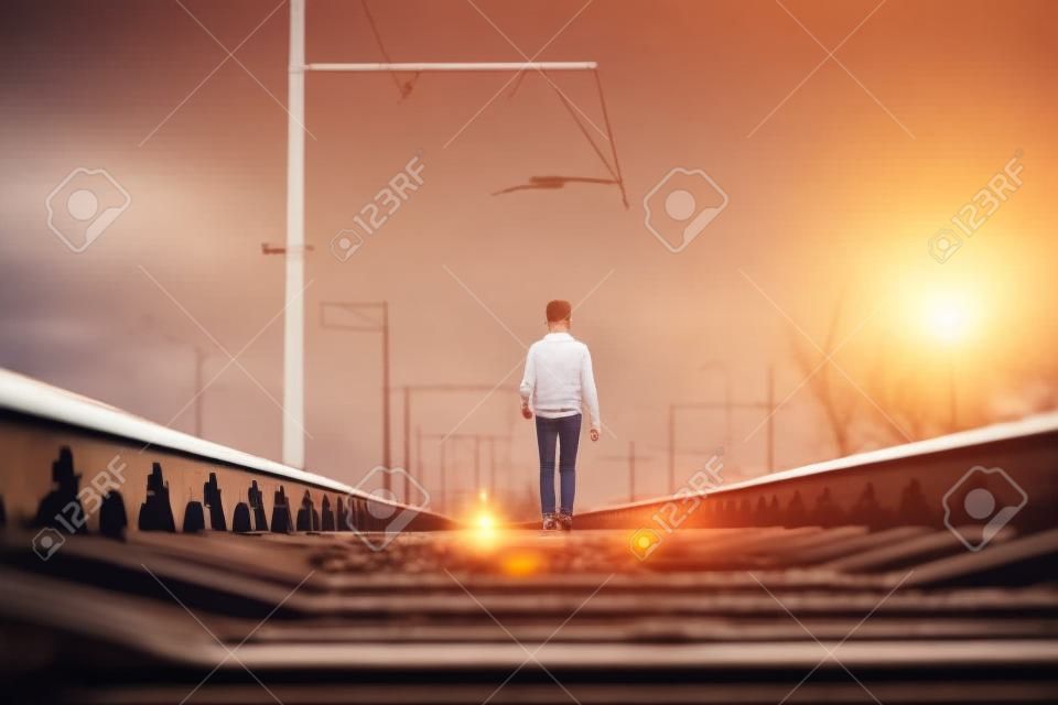 Adolescente sulla ferrovia che cammina con il piccolo cane bianco. Concetto di libertà e solitudine