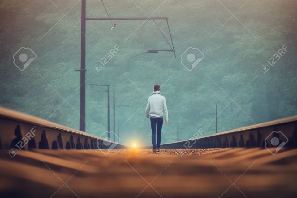Adolescente sulla ferrovia che cammina con il piccolo cane bianco. Concetto di libertà e solitudine