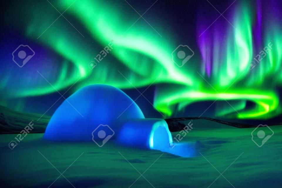 Aurora borealis. Noorderlicht in de winter bergen. Winnelijke scène met gloeiende poollichten en besneeuwde iglo