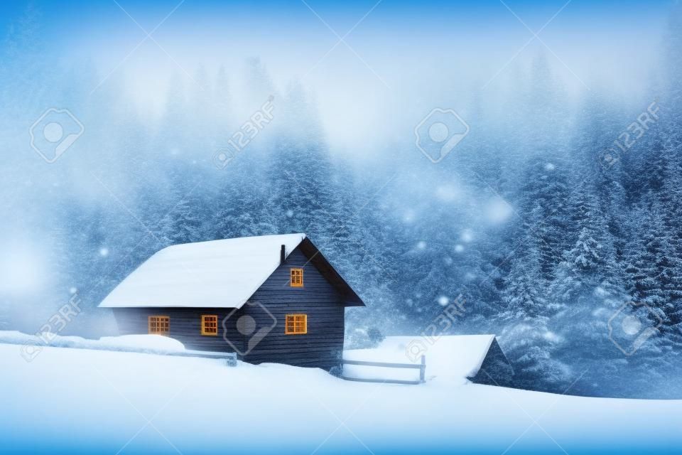 Fantastic winter landscape with wooden house in snowstorm in snowy mountains. Christmas holiday and winter vacations concept
