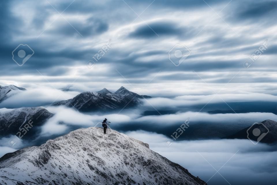 Landscape photographer taking photo of foggy cloudy mountains. Travel concept, landscape photography