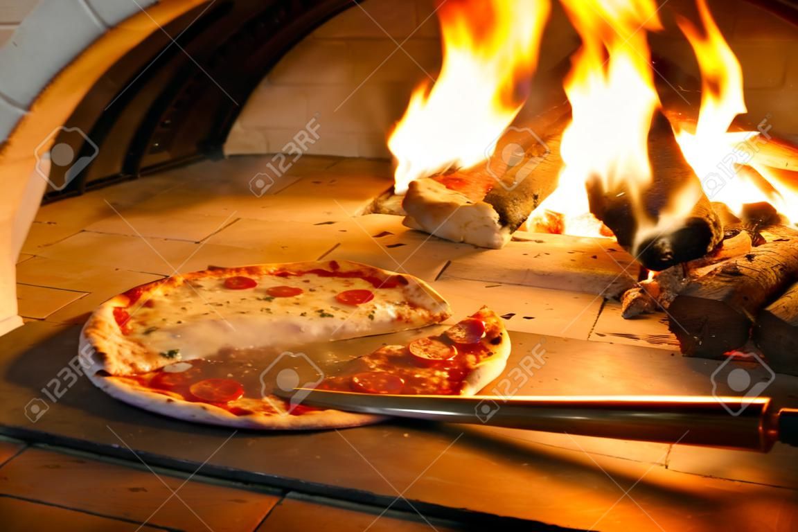 Schließen Sie herauf Pizza im Brennholzofen mit Flamme hinten