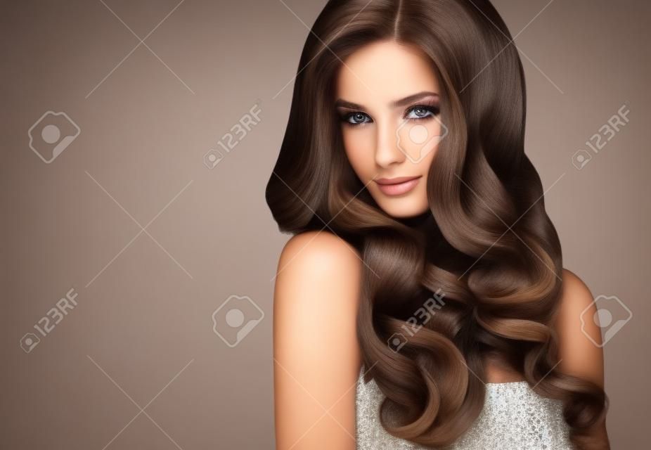褐髮女孩，長而有光澤的波浪捲髮。漂亮的模特與捲曲的髮型。