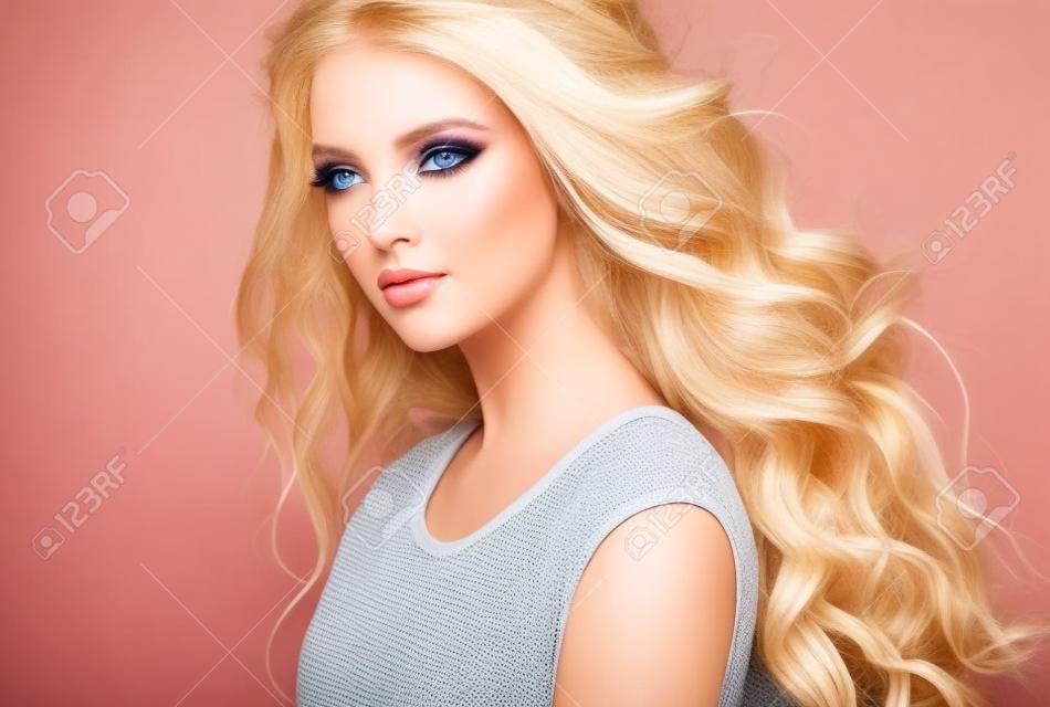 Young, blond haired woman  with voluminous hair. Beautiful model with stylish, loose hairstyle with freely lying curls.and vivid make-up.Flying hair.