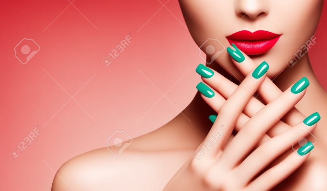 Perfekte Frauenlippen mit idealer Form und durch leuchtend roten Lippenstift und rote Maniküre auf den Nägeln gefärbt. Stilvolles Abendbild für junge Frauen. Mode Make-up und Kosmetik.