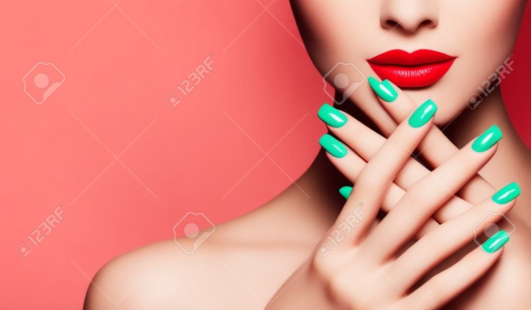Idealne kobiece usta o idealnym kształcie, pomalowane jaskrawoczerwoną szminką i czerwonym manicure na paznokciach. Stylowy wieczorowy wizerunek dla młodych kobiet. Makijaż mody i kosmetyki.