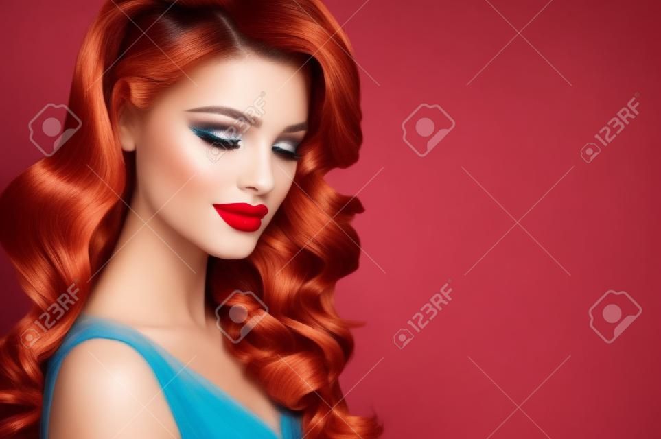 Schönes Model mit langem, dichtem, lockigem Haar und lebendigem Make-up mit rotem Lippenstift. Friseurkunst, Haarpflege und Schönheitsprodukte.