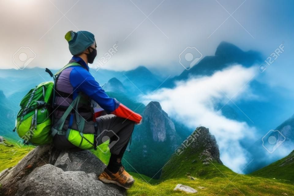 Hiker in mountains enjoying on view of foggy valley in mountains.
Mountains landscape, travel to Asia, happiness emotion, summer hike concept.