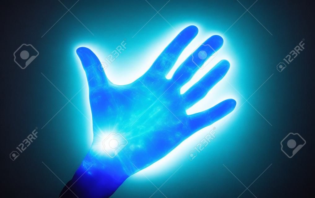UV Ultraviolet light on a hand illustrating the effect of bacteria and viruses on asurface that has not been washed showing the importance of good hygiene and hand washing espically during a pandemic such as Covid-19.