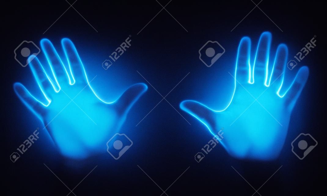 Ludzkie dłonie świecące od światła ultrafioletowego uv pokazujące bakterie i wirusy na czarnym tle, pokazujące znaczenie mycia rąk.