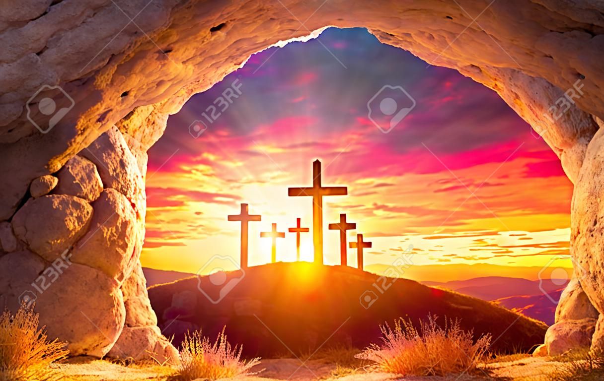 Auferstehungskonzept - leeres Grab mit drei Kreuzen auf einem Hügel bei Sonnenaufgang