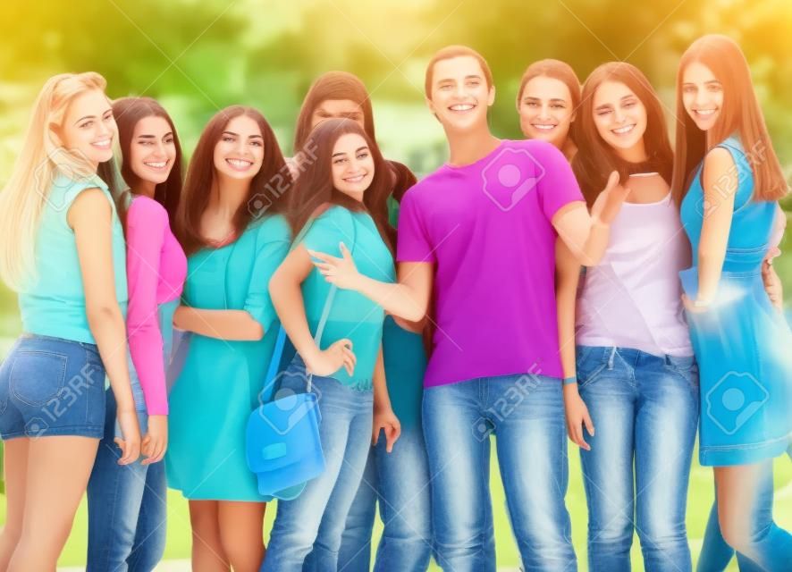 Group of flirting young girls with happy smiling popular boy