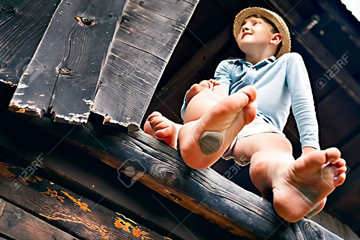 Barfuß Junge sitzt auf Scheune Leiter