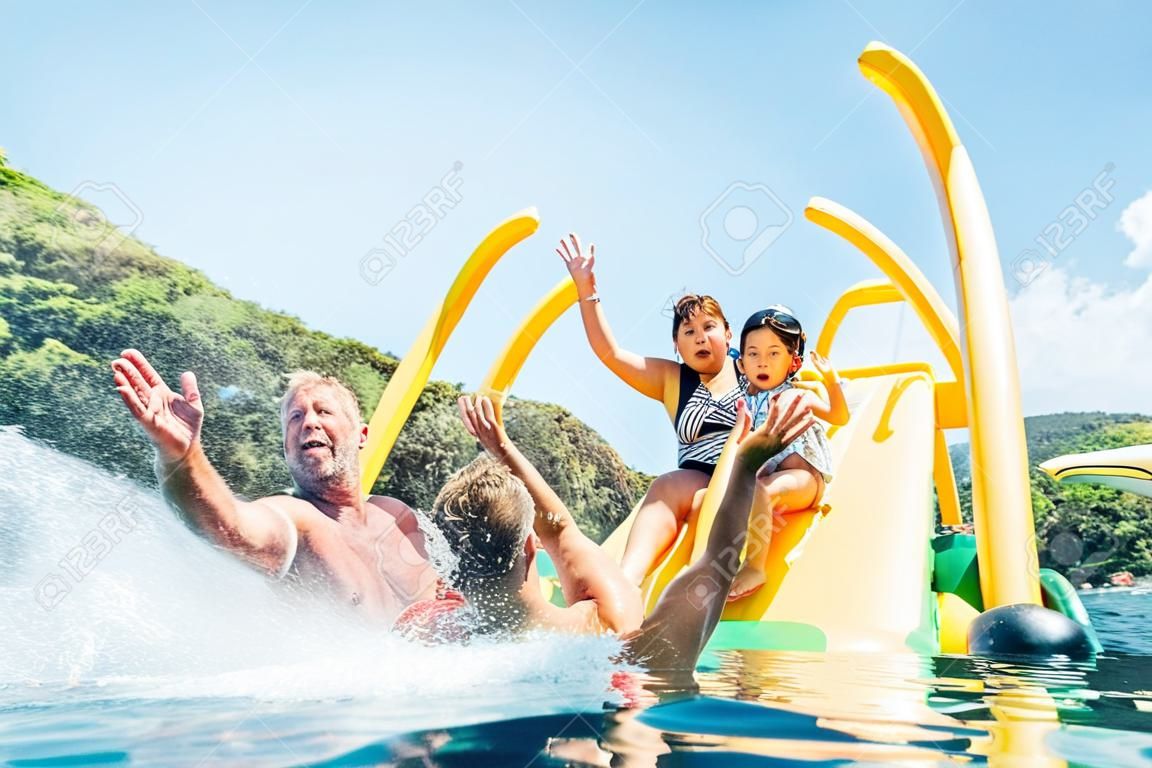 Felice famiglia pazza alza le mani sul catamarano galleggiante del parco giochi mentre si godono il viaggio in mare mentre hanno le vacanze estive