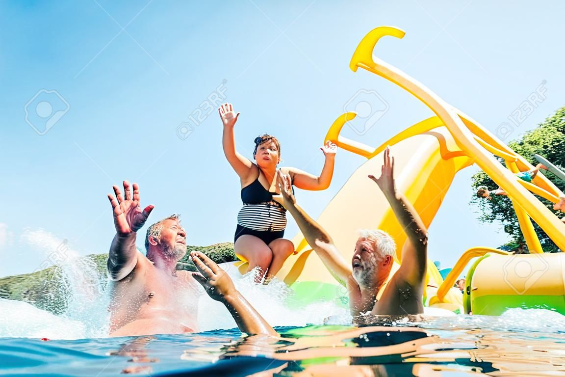Glückliche verrückte Familie Hände hoch auf schwimmenden Spielplatzrutsche Katamaran, während sie eine Seefahrt genießen, während sie Sommerferien haben