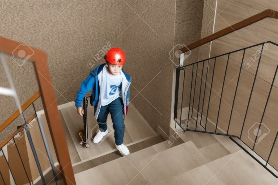 Tiener skateboarder jongen met een skateboard gaat omhoog via trap naar huis.