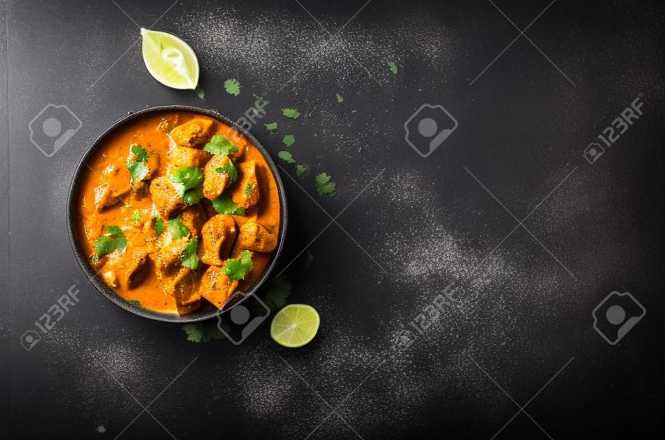 印地安黃油雞用在碗，香料，黑背景的印度大米。文本的空間。黃油雞，傳統印地安盤。頂視圖。雞tikka masala。印度美食的概念。高架