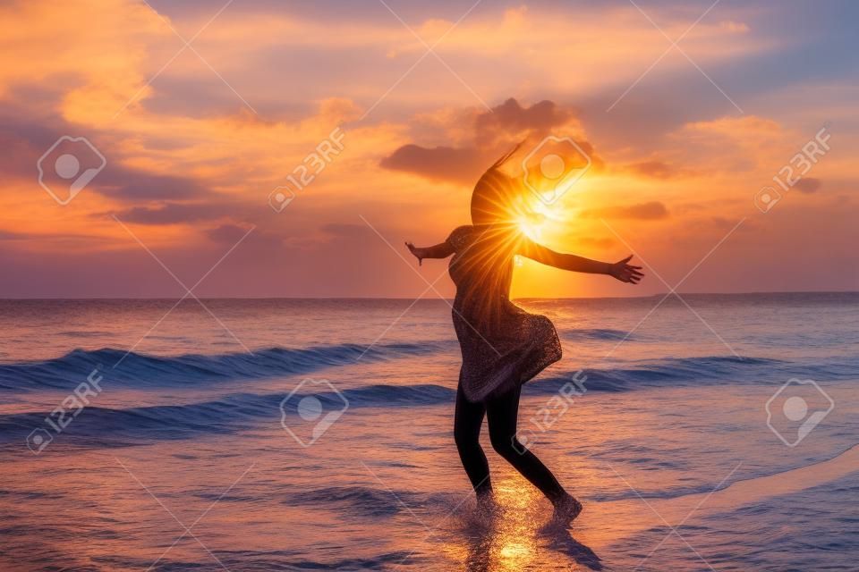 愉快的婦女跳在海上日落