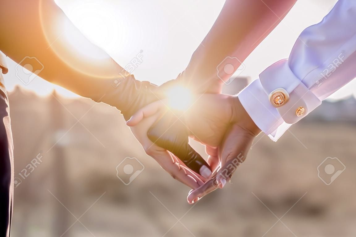 Handen vasthouden met trouwringen op de achtergrond van zonlicht