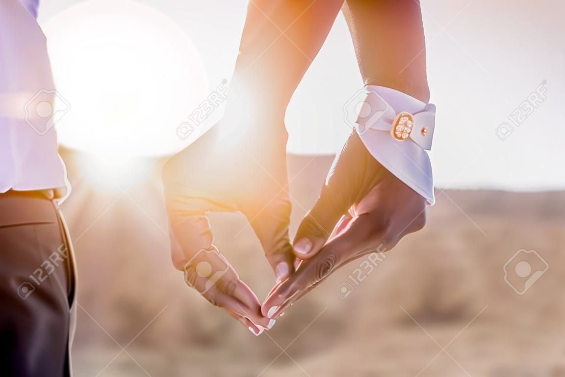 Segurando as mãos com anéis de casamento no fundo da luz solar