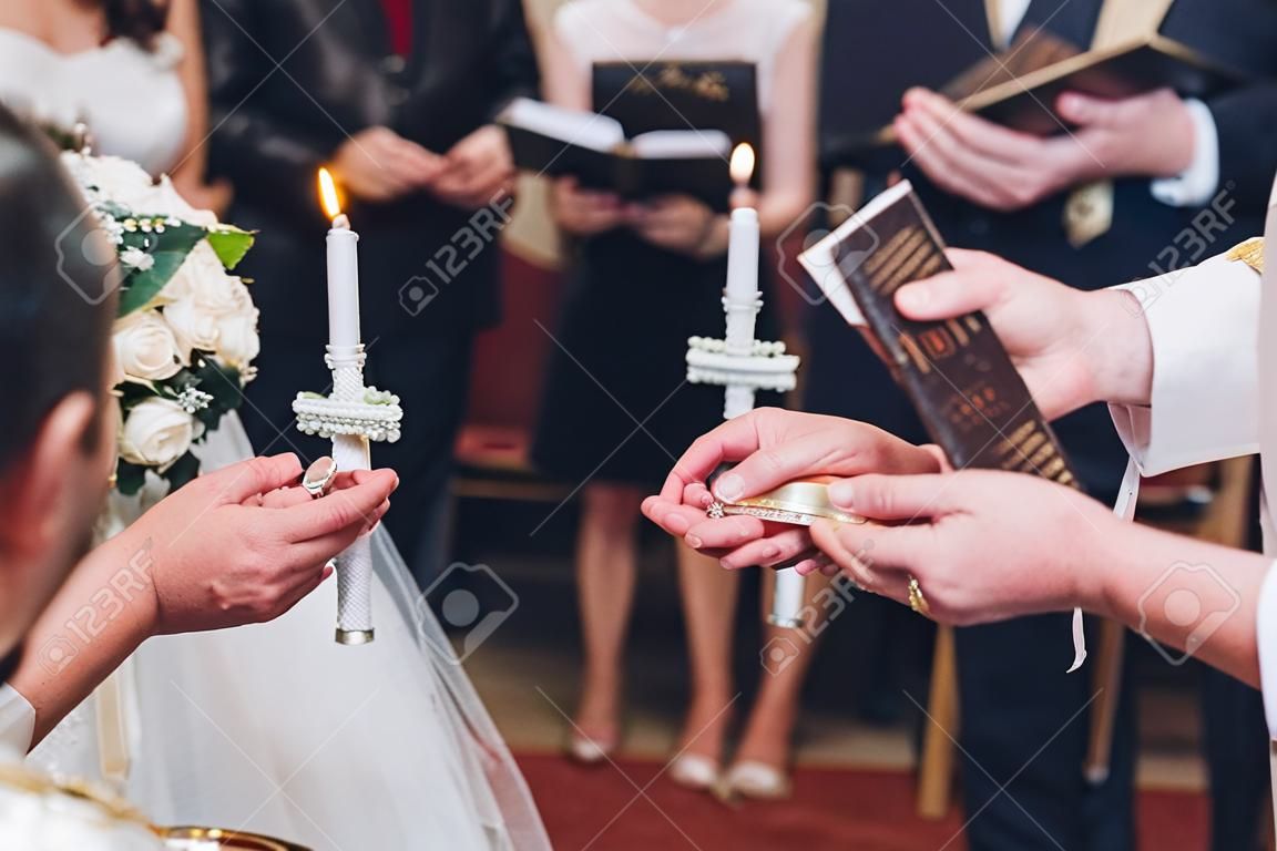 exchanging wedding rings. priest putting on golden wedding rings on fingers bride and groom in church at wedding matrimony. traditional religious wedding ceremony