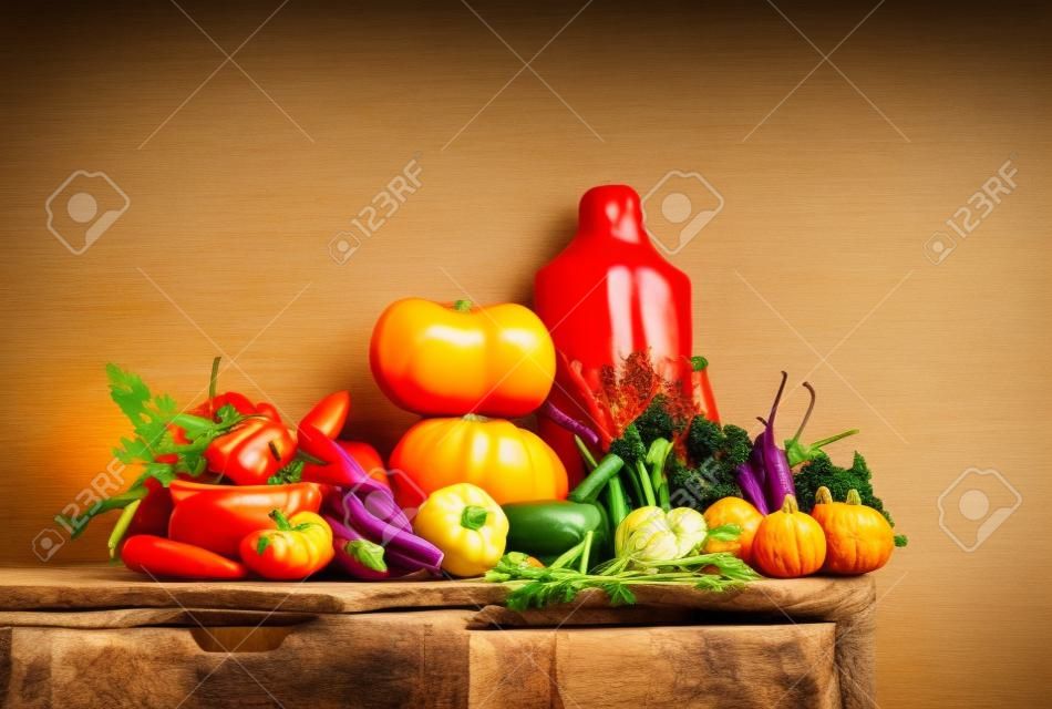Fall seasonal vegetarian food ingredients variety. Assortment of Autumn vegetables for healthy cooking over rustic kitchen cupboard, white wall background, copy space. Local market organic produce