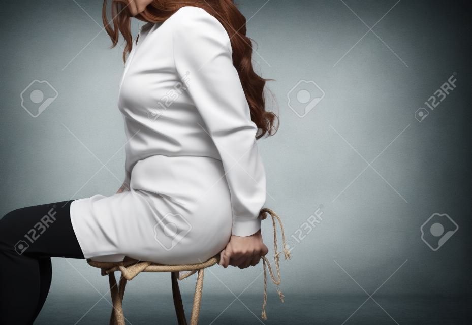 Woman's hands tied with rope sitting chair kidnapping concept