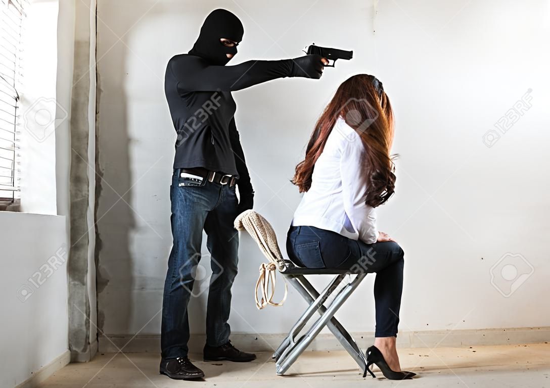 El ladrón ladrón apunta con la pistola a la cabeza está a punto de matar a la mujer rehén, crimen