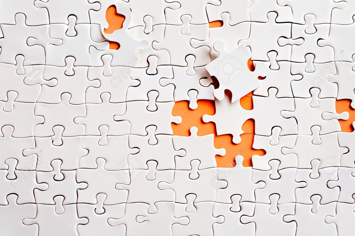 Top view flat lay of paper plain white jigsaw puzzle game texture incomplete or missing piece, studio shot on an orange background, quiz calculation concept