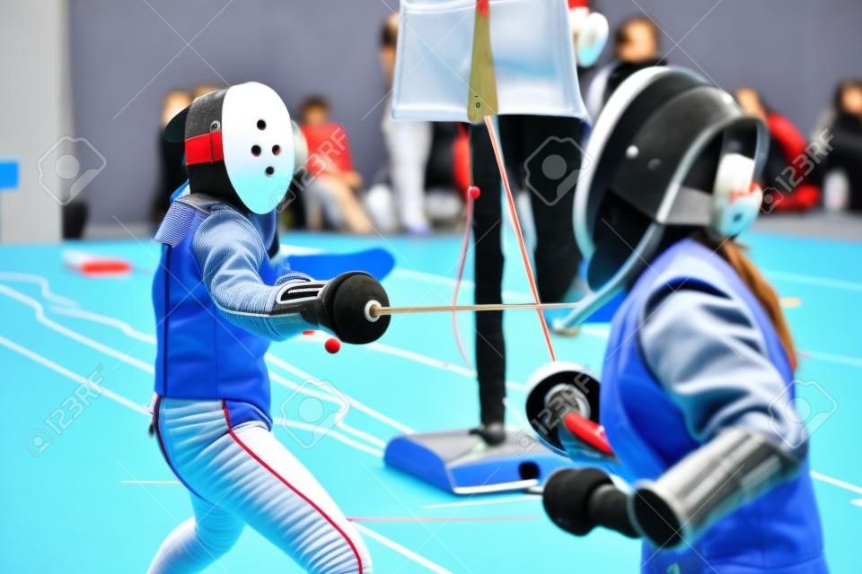 Two young girls fencers having fencing duel on tournament
