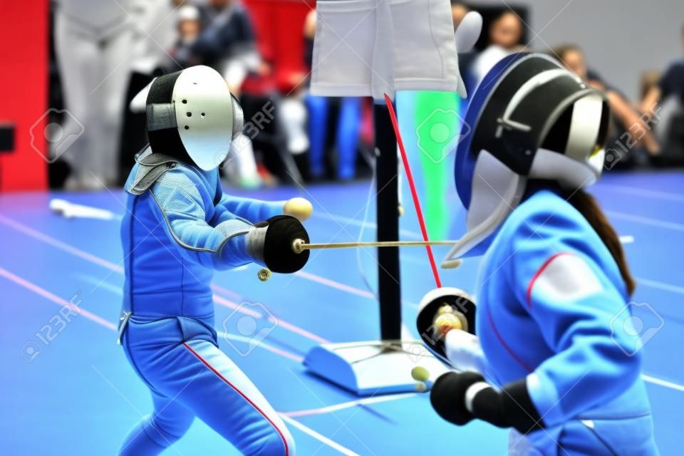 Due giovani ragazze schermitrici che hanno duello di scherma durante il torneo