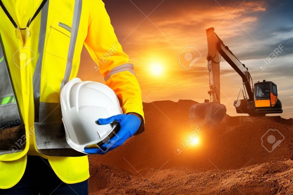 工程师或安全主任在日落时施工现场用挖掘机安装硬帽