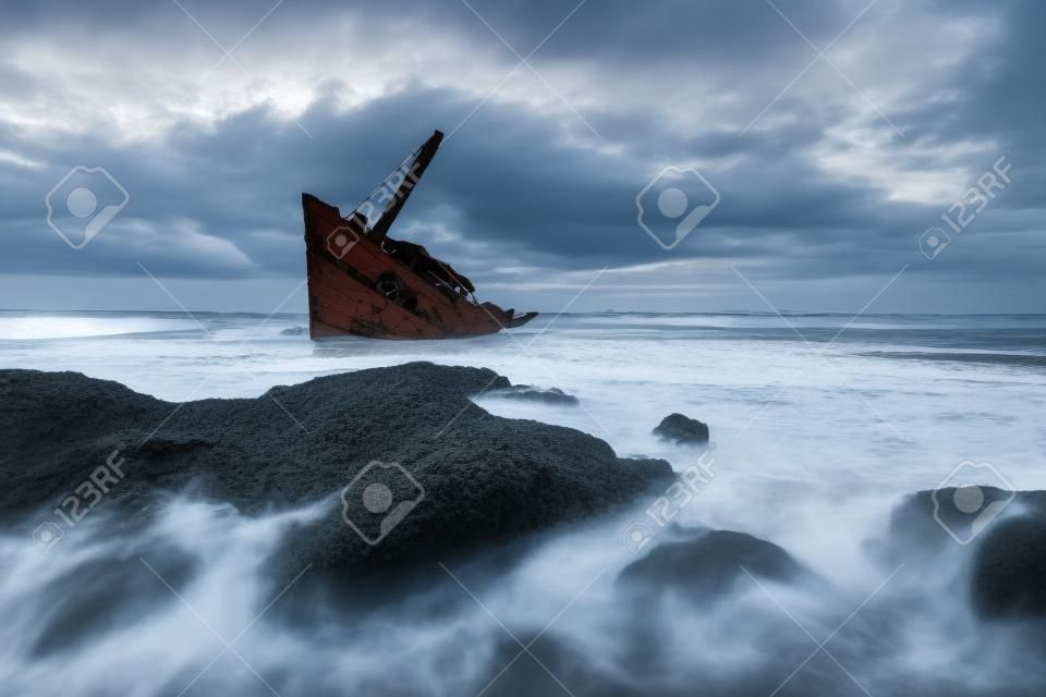 Une vieille épave ou un bateau abandonné se tient sur la plage