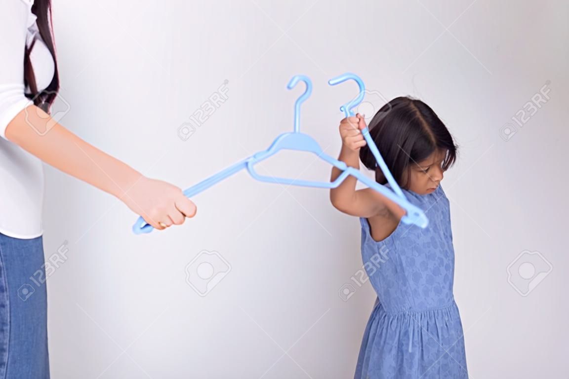 Mother is punishing daughter by hitting with a hanger.Family violence concept
