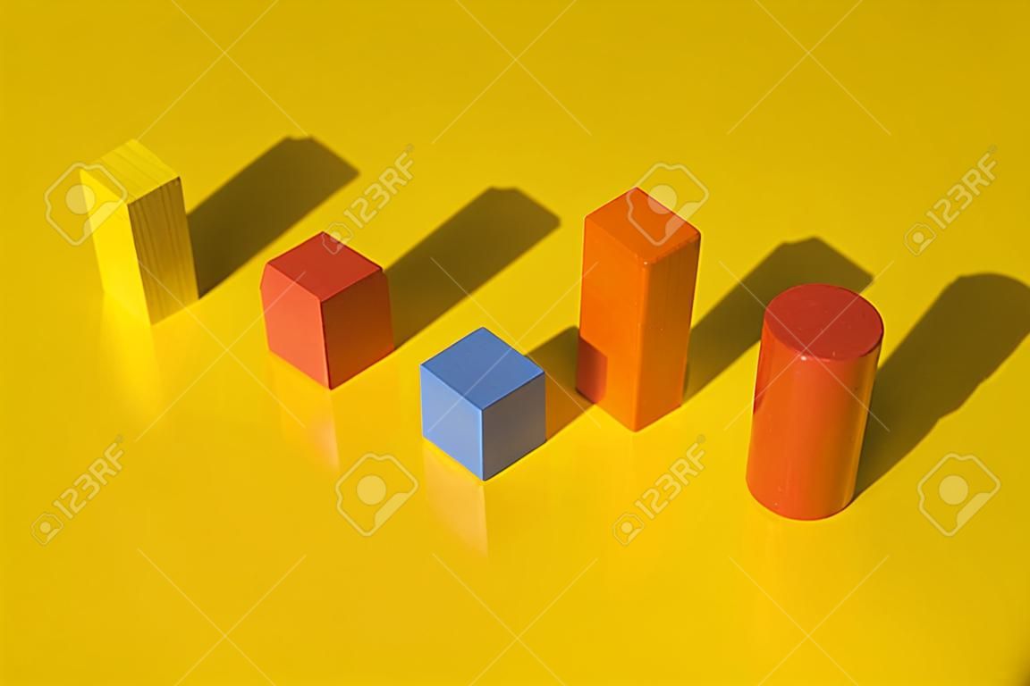 Wooden building blocks toy with shadow isolated on yellow background.
