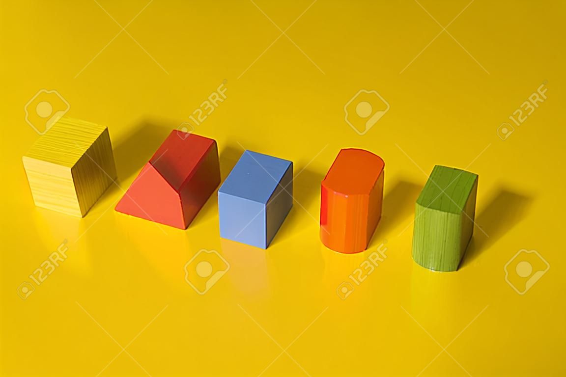Wooden building blocks toy with shadow isolated on yellow background.