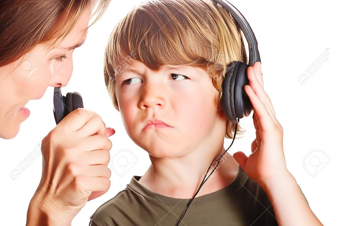 A mother pulls the headphone off of her son to tell him something