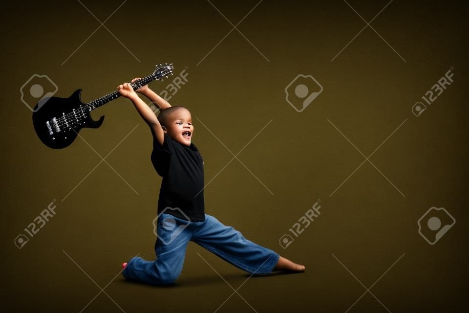 Young boy with black electric guitar raised up over his head as if he's going to smash it.